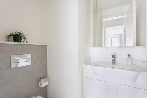La salle de bains blanche est pourvue d'un lavabo et d'un miroir. dans l'établissement Frank Porter - Ahad Residences, à Dubaï
