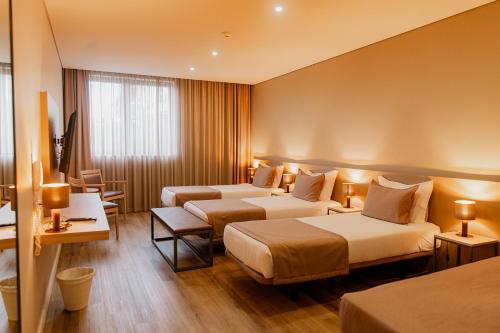ein Hotelzimmer mit 3 Betten und einem Fenster in der Unterkunft Meu Hotel Porto Gandra in Paredes