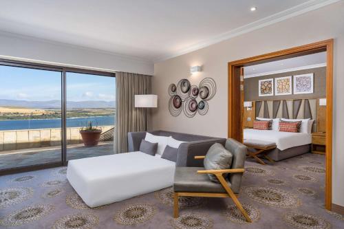 a living room with a couch and a bed and a window at Arabella Hotel, Golf and Spa in Kleinmond