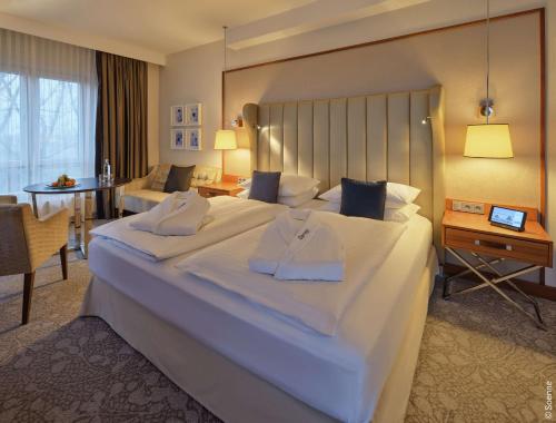 ein Hotelzimmer mit einem großen Bett und einem Tisch in der Unterkunft Dorint Hotel Bonn in Bonn