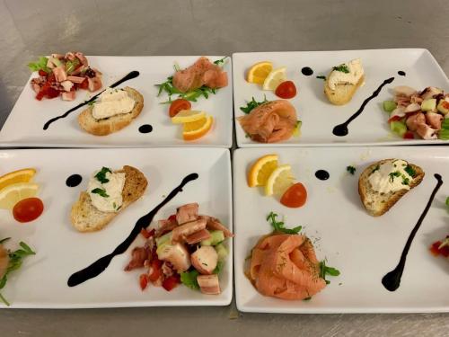 vier weiße Platten mit verschiedenen Arten von Lebensmitteln in der Unterkunft Hotel Nizza Frontemare Superior 3 Stelle in Lido di Jesolo