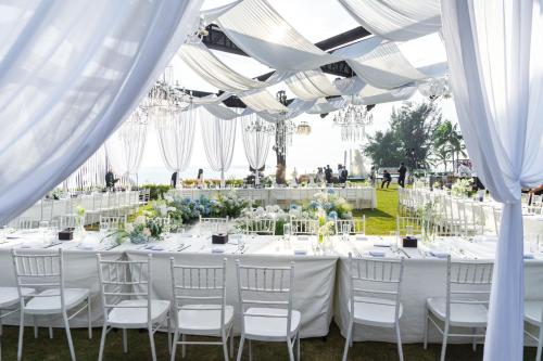a wedding reception with white tables and chairs under white drapes at Shenzhen Marriott Hotel Golden Bay in Shenzhen