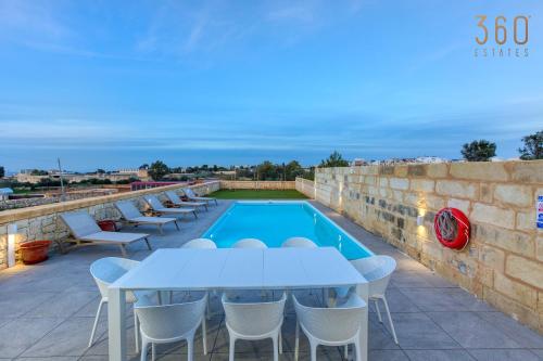 een patio met tafels en stoelen naast een zwembad bij LUX Villa with Private Pool, BBQ & Rooftop Oasis by 360 Estates in Kalkara