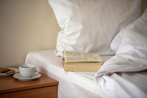 a book and a cup of coffee on a bed at Royal SPA Residence in Birštonas
