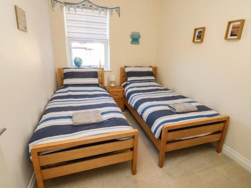 two twin beds in a room with a window at 9 Seaford Sands in Paignton