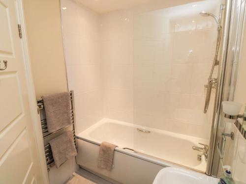 a white bathroom with a tub and a sink at 9 Seaford Sands in Paignton