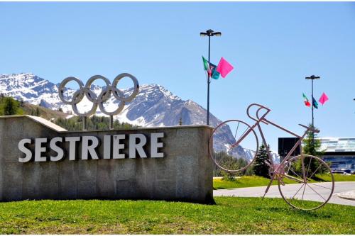 a sign for the olympics in front of a mountain at Villaggio Olimpico in Sestriere
