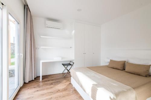 a white bedroom with a bed and a window at Vilas do Olival in Ponta Delgada