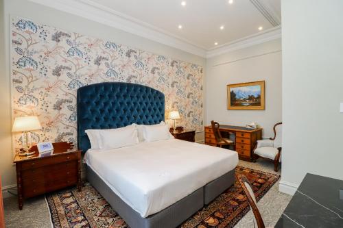 a bedroom with a large bed with a blue headboard at The Monarch Hotel in Johannesburg