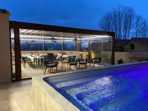 - une piscine à côté d'une terrasse avec une table et des chaises dans l'établissement La Manufacture D'oriano LES NUITS AU VILLAGE, à Montegrosso
