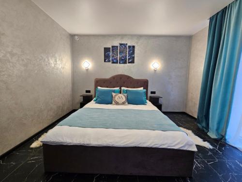a bedroom with a large bed with blue pillows at Villa Magnat in Berehove