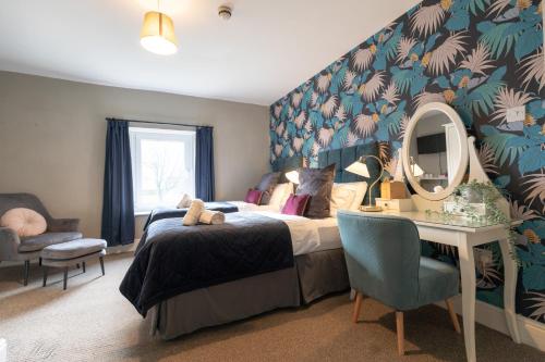a bedroom with a bed and a desk with a mirror at Wyndgrove House in Seahouses