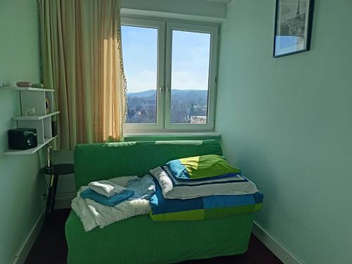 un sofá verde en una habitación con ventana en - PANORAMA -, en Sopot