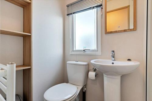 a bathroom with a toilet and a sink and a window at Tattershall Lakes: Sally's Superior Stay in Tattershall