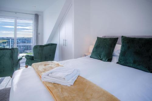 a bedroom with a white bed with two green chairs at Oasis - 2 Bedroom Apartment - Ocean Breeze in Port-Eynon