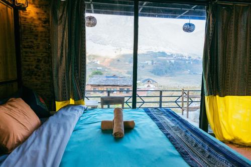 a teddy bear sitting on a bed in a room with a window at Plum Eco House in Sa Pa