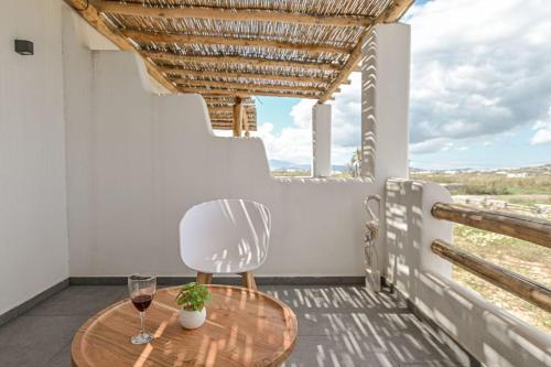 un tavolo e una sedia su un balcone con bicchieri da vino di Luxury Naxos Villa | 4 Bedrooms | Villa Charlotte Linlin | Panoramic Sea Views | Naxos ad Agia Anna Naxos