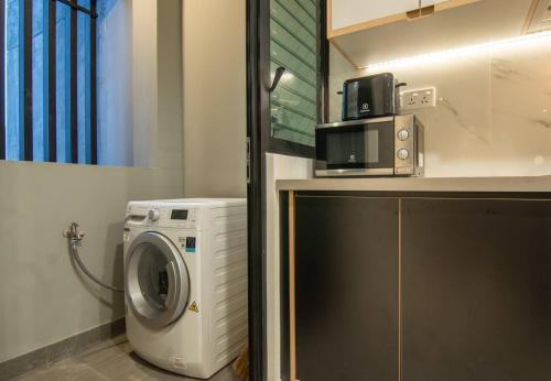 a kitchen with a washing machine and a microwave at Luxury 2 or 3BR Apartment in Dist 1, Pool and airport pickup in Ho Chi Minh City