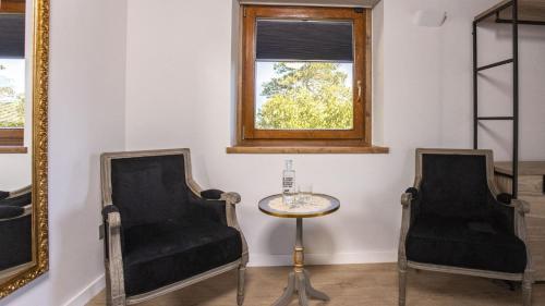two chairs and a table in a room with a window at Abbatissa Hotel Restaurant in Sant Joan de les Abadesses