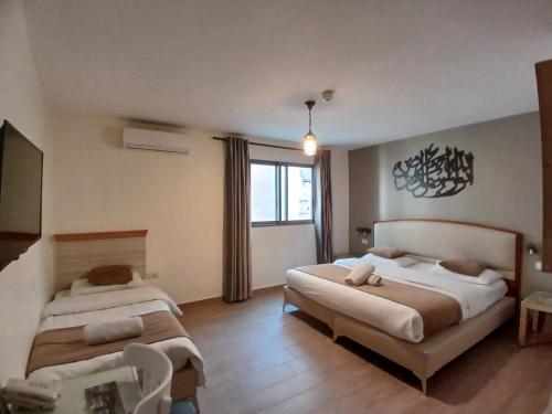 1 dormitorio con 2 camas y ventana en Layaali Amman Hotel en Amán