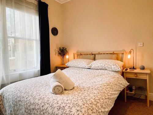 1 dormitorio con 1 cama con colcha blanca y ventana en Bright, spacious apartment with off-road parking en Bath