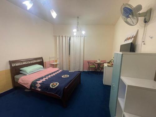 a bedroom with a bed and a table with a fan at Salahuddin Metro Home Stay in Dubai