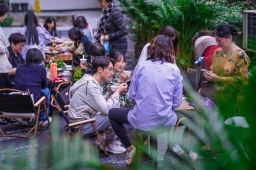 a group of people sitting at tables in a garden at Chengdu Local Tea Hostel - Short Walk To Taikooli - Chill & Social Coffee Lounge - Metro downstairs - Free Activities - Friendly English Speaking Staff - Tibet, Panda, Buddha & Snow Mountain Tours in Chengdu