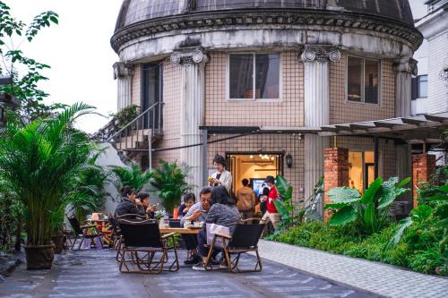 un gruppo di persone seduti a un tavolo di fronte a un edificio di POSHPACKER·Chengdu Local Tea Hostel a Chengdu