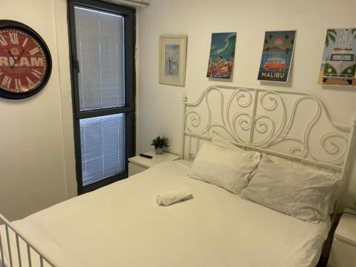 a bedroom with a white bed with a clock on the wall at מגדלי המרינה in Herzliyya B