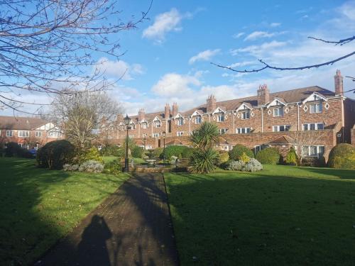 a large brick building in front of a green yard at Charming apartment with big terrace in Sandymount in Dublin