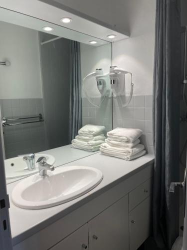 a bathroom with a sink and a mirror at Hôtel-Restaurant "Les Rochers" in La Balme-de-Sillingy