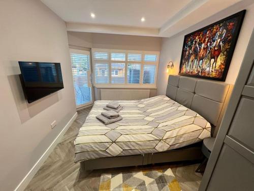 a bedroom with a bed and a painting on the wall at One of a kind 3-bed maisonette with BBQ & sauna in Woodford