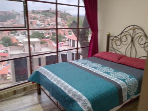 ein Schlafzimmer mit einem Bett und einem großen Fenster in der Unterkunft Santa Pacha in Sucre