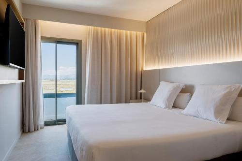 a bedroom with a large bed and a large window at Prinsotel La Dorada & Spa in Playa de Muro