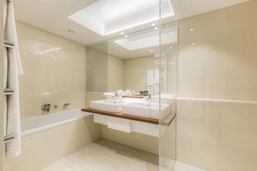 ein Badezimmer mit einem Waschbecken, einer Badewanne und einem Spiegel in der Unterkunft Vienna Grand Apartments DANUBE in Wien