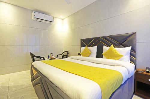 a bedroom with a large bed with yellow and white sheets at Hotel NASHA Unit By Worth New Delhi in New Delhi