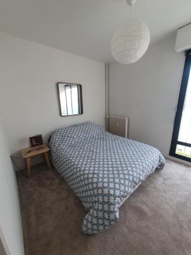 een slaapkamer met een bed, een tafel en 2 ramen bij L'atelier cosy in Beaune