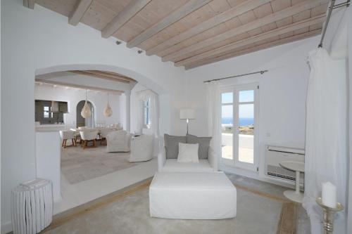 a white living room with a white couch and a table at Awesome Mykonos Villa - 5 Bedrooms - Villa Houlston - Great Panoramic Sea Views in Fanari