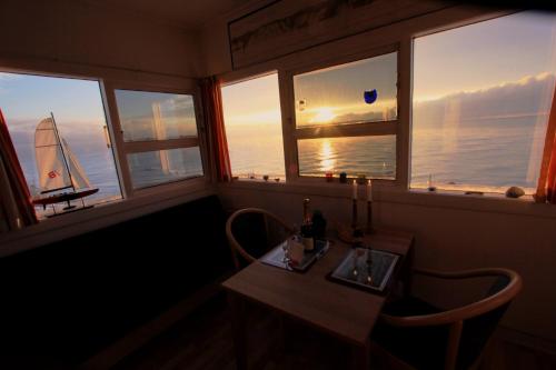 Cette chambre dispose de fenêtres avec une table et un voilier. dans l'établissement The Lighthouse Cabin, à Borre