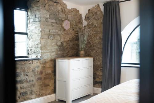 a bedroom with a white dresser and a stone wall at Unicorn House Hot Tub Near Barnard Castle in Barnard Castle