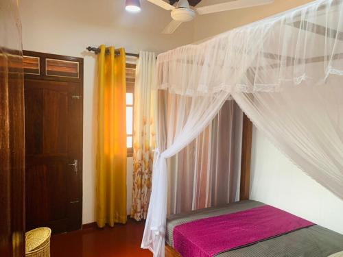 a bedroom with a bed with a canopy and a window at No 31 in Galle