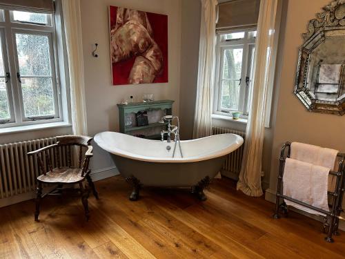 ein Badezimmer mit einer Badewanne, einem Stuhl und Fenstern in der Unterkunft The Old Rectory in Kings Lynn