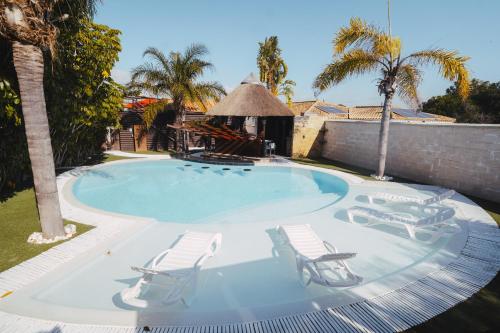 a swimming pool with two lounge chairs and a palm tree at Villa Campito in El Puerto de Santa María