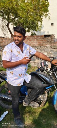 un hombre está de pie junto a una motocicleta en SK HOTEL TOUR AND TRAVEL, en Chittorgarh