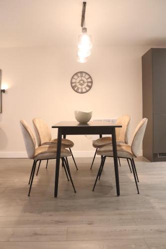 a dining room table with chairs and a clock on the wall at The Nest at Hemel Hempstead in Hemel Hempstead