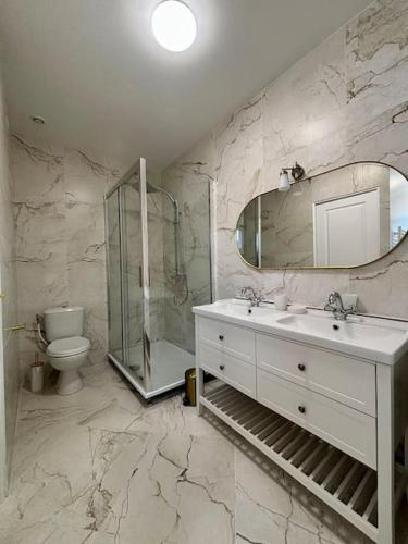 une salle de bain avec un lavabo, des toilettes et un miroir dans l'établissement Les Villas de Puys : Luxueuse Villa 7-9Pers, à Dieppe