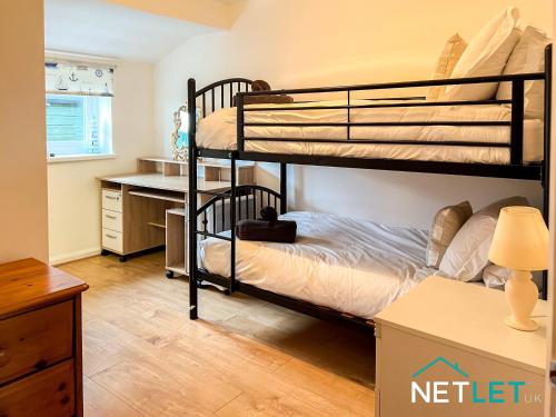 a bedroom with two bunk beds and a desk at Zephyr Heights in Pembrokeshire