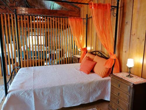 a bedroom with a canopy bed with orange curtains at Country House - Hippie Garden in Vieira do Minho