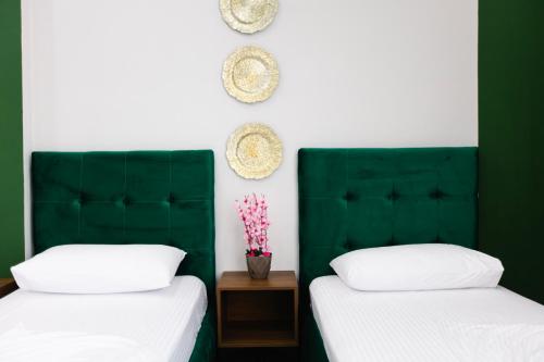 two beds with green headboards in a room at Andor Luxury Hotel & Duplex in Durrës