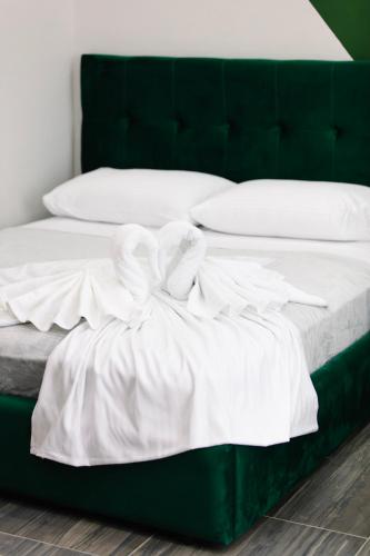 a green bed with white sheets and pillows at Andor Luxury Hotel & Duplex in Durrës